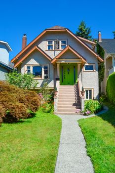 Family house with the pathway over front yard lawn on blue sky background.