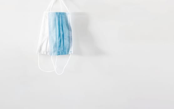 a pair of hanging surgical masks isolated on a white background. Personal care and virus prevention