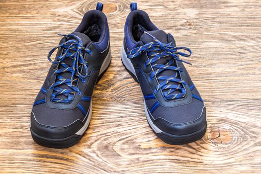 black and blue outdoor empty clean lightweight waterproof sneakers on wooden surface