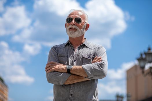 Old rich man with beard and sun glasses on street posing and smiling, portrait