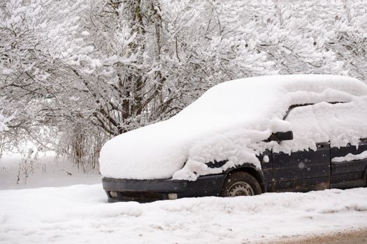 Old dirty car covered by thick snow layer with selective focus.