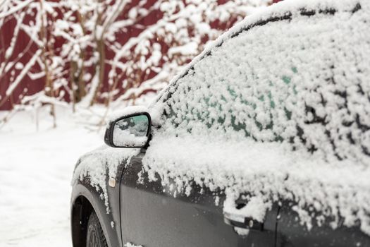 Dirty car covered by thick snow layer with selective focus.