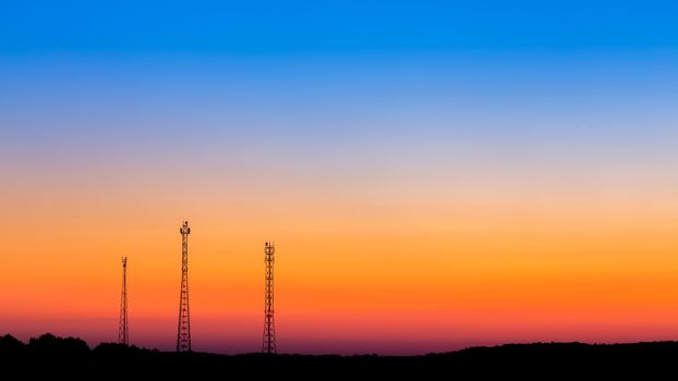 three communication towers far on gradient sunrise sky background with large copyspace