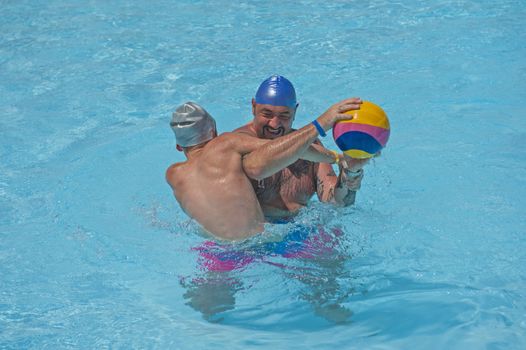 Father and son having fun playing water polo in tropical hotel resort swimming pool on vacation