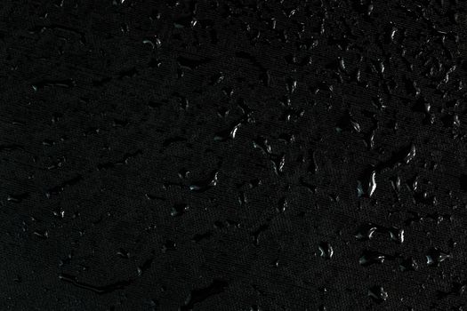 black flat rubber surface with water drops macro background.