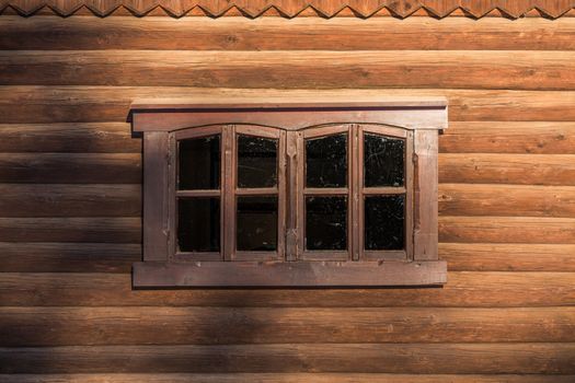 log wall with one centered rectangular window under sunlight with blurry shadows