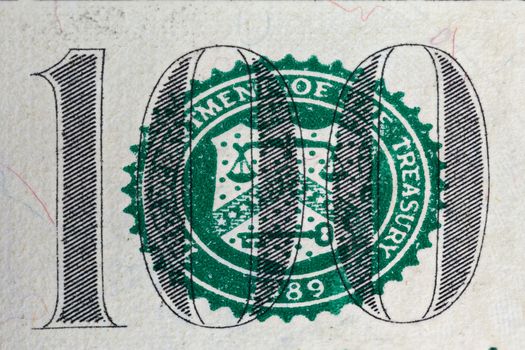 A number of one hundred on dollar bill and United States Treasury Department symbol in macro magnification.