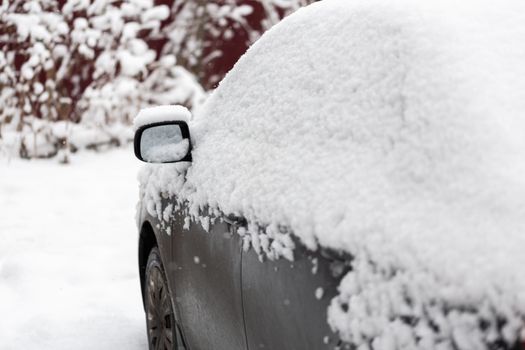 Dirty car covered by thick snow layer with selective focus.