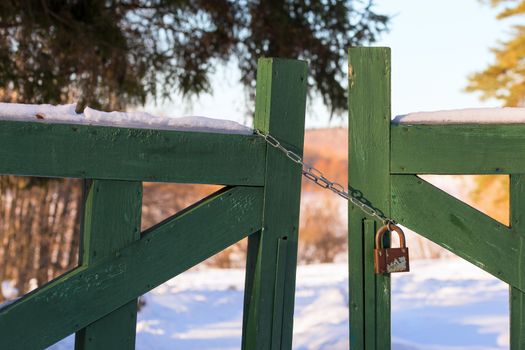 closed wooden gate at winter daylight with chain and padlock