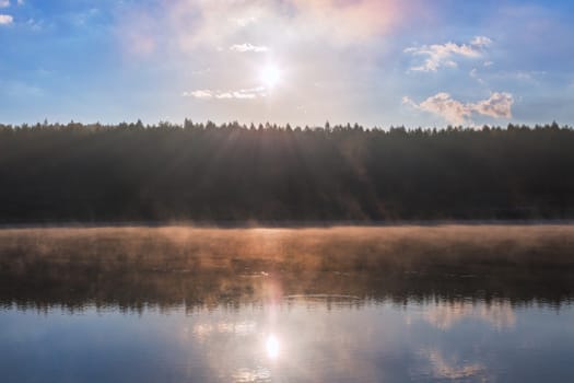 foggy riverside at summer sunrise with flat forest wall