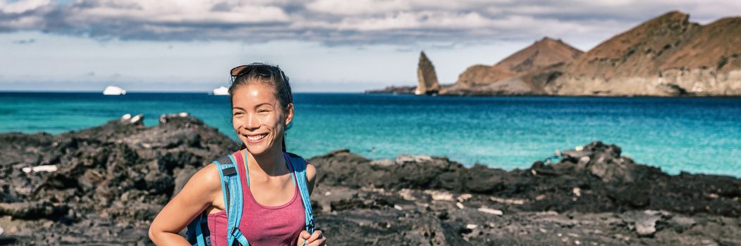 Panoramic banner of Galapagos tourist walking on Santiago Island in Galapagos Islands. Pinnacle Rock and Bartolome Island in background. Famous Galapagos cruise ship tour destination.