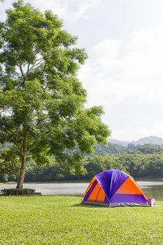 Tourist dome tent camping in forest camping site at lake side