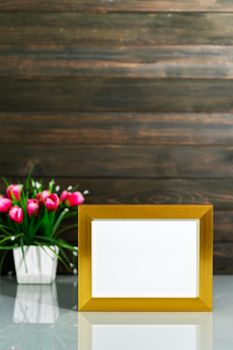 Picture mock up with golden frame and Artificial flower vase bouquet over table with wood wall background