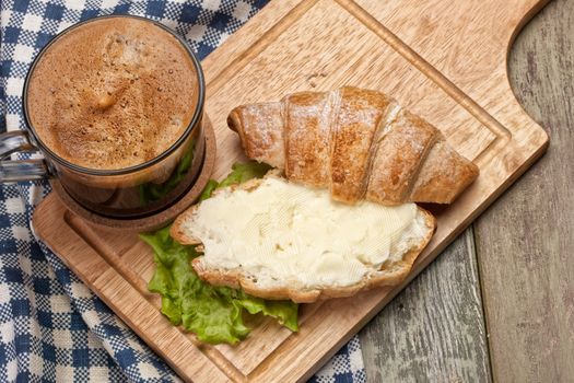 Bread, butter, coffee and greenery on a studio canvas background