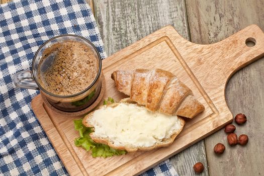 Bread, butter, coffee and greenery on a studio canvas background