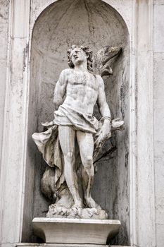 Carved stone statue of Saint Sebastian shot with an arrow. Facade of San Stae church, Venice.