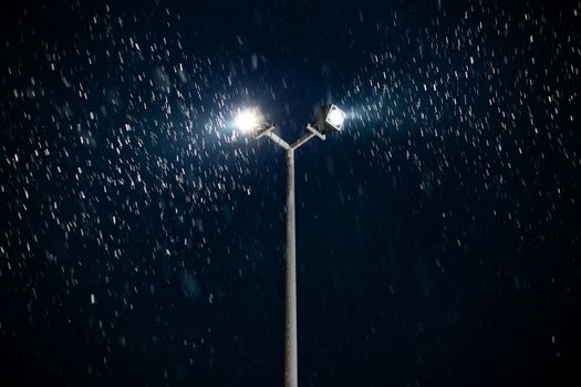 modern double light spot on lamp post at winter night snowfall.