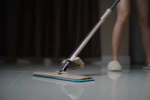 Woman using a flat wet-mop cleaning floor in the house. protect virus covid-19