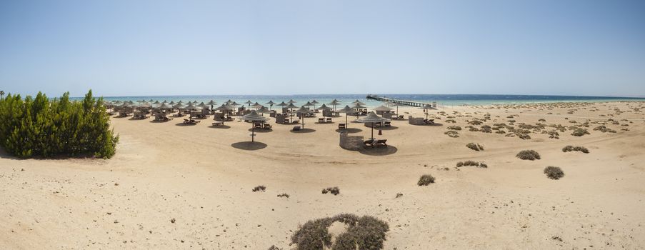 Landscape panoramic view of a sandy beach with sunbeds at tropical luxury hotel resort