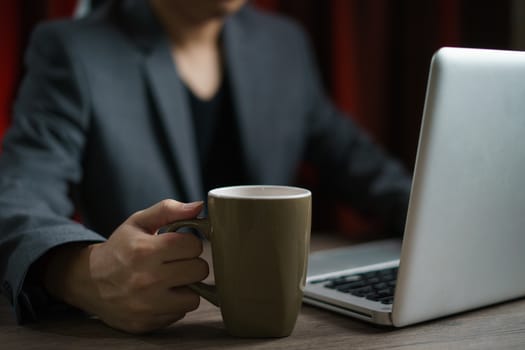 Man working from home using computer and drinking cup of tea, closeup portrait indoor.