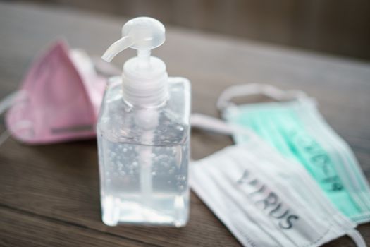 Antibacterial transparent hand sanitizer gel in a plastic bottle with surgical mask corona virus (covid-19) text written.