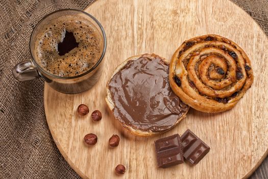 Cup of coffee, bread, butter and nuts on a wooden table