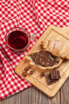 Cup of tea and croissant on a tablecloth