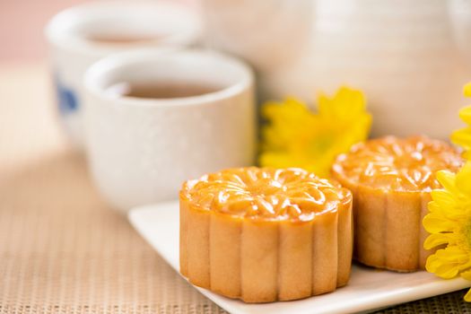 Tasty baked egg yolk pastry moon cake for Mid-Autumn Festival on bright wooden table background. Chinese festive food concept, close up, copy space.