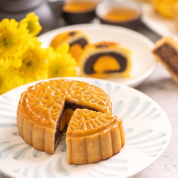 Tasty baked egg yolk pastry moon cake for Mid-Autumn Festival on bright wooden table background. Chinese festive food concept, close up, copy space.