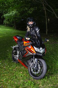 young woman about to get on a sport motocycle, in a park