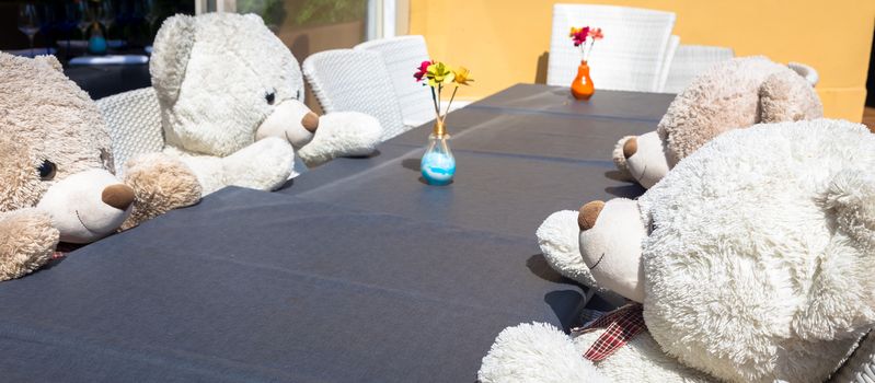 A group of Teddy Bears sitting at the a table and ready for a lunch or a meeting