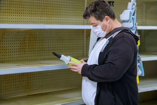 Supermarket interior with man medical protective face mask choosing in shop with empty shelves during the Coronavirus COVID-19