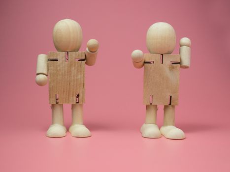 2 wooden dolls standing talk gestures On the pink background.
Concept of social contact from wood dolls.