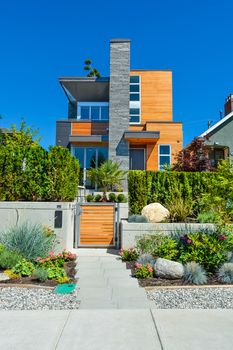 Luxury family house with delicatedly landscaped front yard. New modern residential house with concrete pathway in front