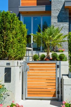 Entrance gate of new luxury family house with landscaped front yard. Modern residential house with concrete pathway through the gate