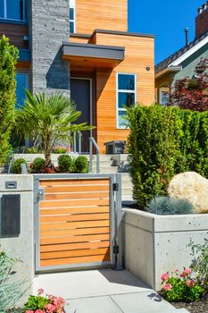 Entrance of new luxury family house with landscaped front yard. Modern residential house with concrete pathway through the gate