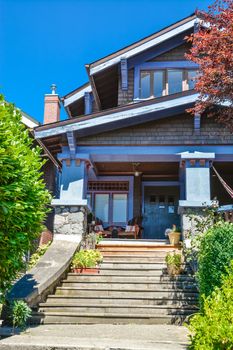 Wooden stairway to main entrance residential house with wooden chairs under the porch