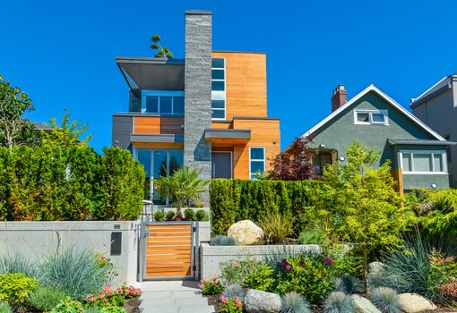 Luxury family house with delicatedly landscaped front yard. New modern residential house with concrete pathway in front