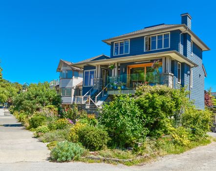 Family house with weedy front yard on blue sky background. Residential house with glass borders on the patio