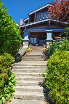 Concrete and wooden stairway to main entrance residential house with wooden chairs under the porch