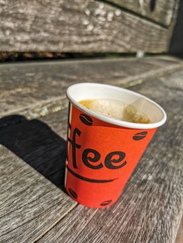 Red paper cup with coffee to go on wooden ground. Leherheide, Bremerhaven.
