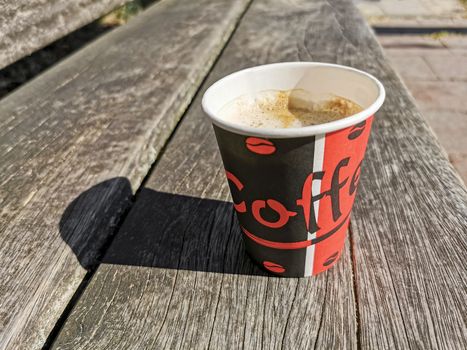 Red paper cup with coffee to go on wooden ground. Leherheide, Bremerhaven.