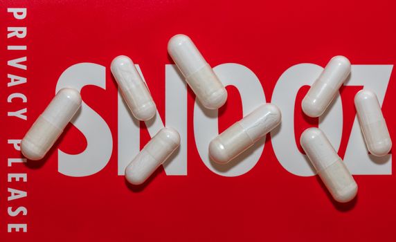 Close-up shot of white pills on red snoozing sign with soft focus background. Background with Snooz and Privacy please words on it
