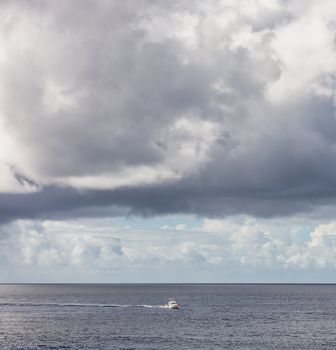 Diving boat sailing by the island of Cozumel in Mexico. Stormy weather, clouds and rain in the background