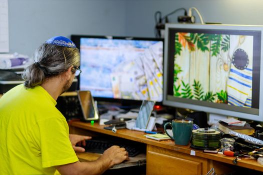 Jewish man designer working home on his typing texting on computer in a at office desk wooden table