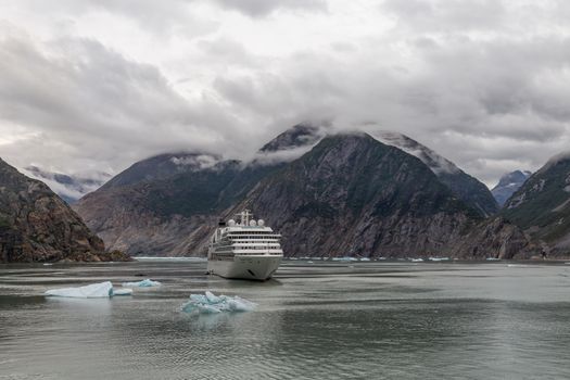Tracy Arm Fjord, Alaska, USA - August 23, 2018: Seabourn Sojourn cruise ship drifting with small icebergs floating around and mountains behind it