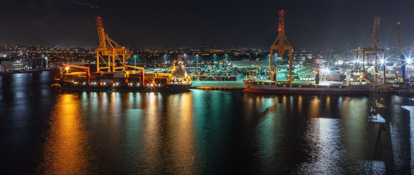 Bridgetown port, Barbados, West Indies - May 1, 2020: Night shot. Long exposure. Bridgetown port with loading cranes and cargo ships being loaded with containers. Beautiful lights.