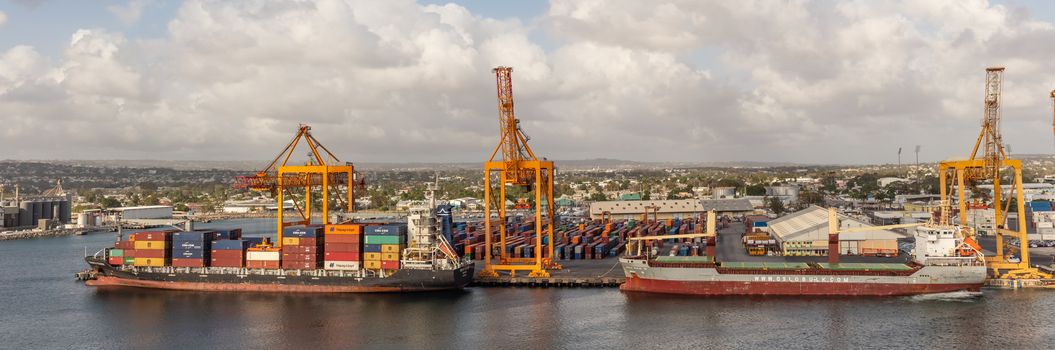 Bridgetown port, Barbados, West Indies - May 2, 2020: Bridgetown port with loading cranes and cargo ships being loaded with containers