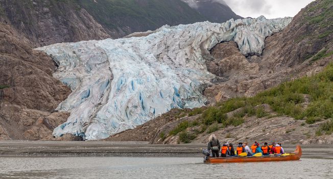 Davidson Glacier, Alaska, US - June 29, 2018: Tourists and a guide drifting in a canoe next to the glacier.