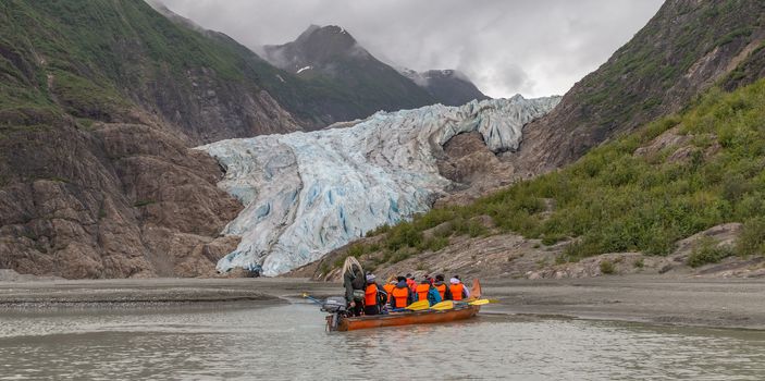 Davidson Glacier, Alaska, US - June 29, 2018: Tourists and a guide sailing in a canoe towards Davidson Glacier
